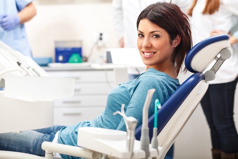 A woman in a dental chair smiling